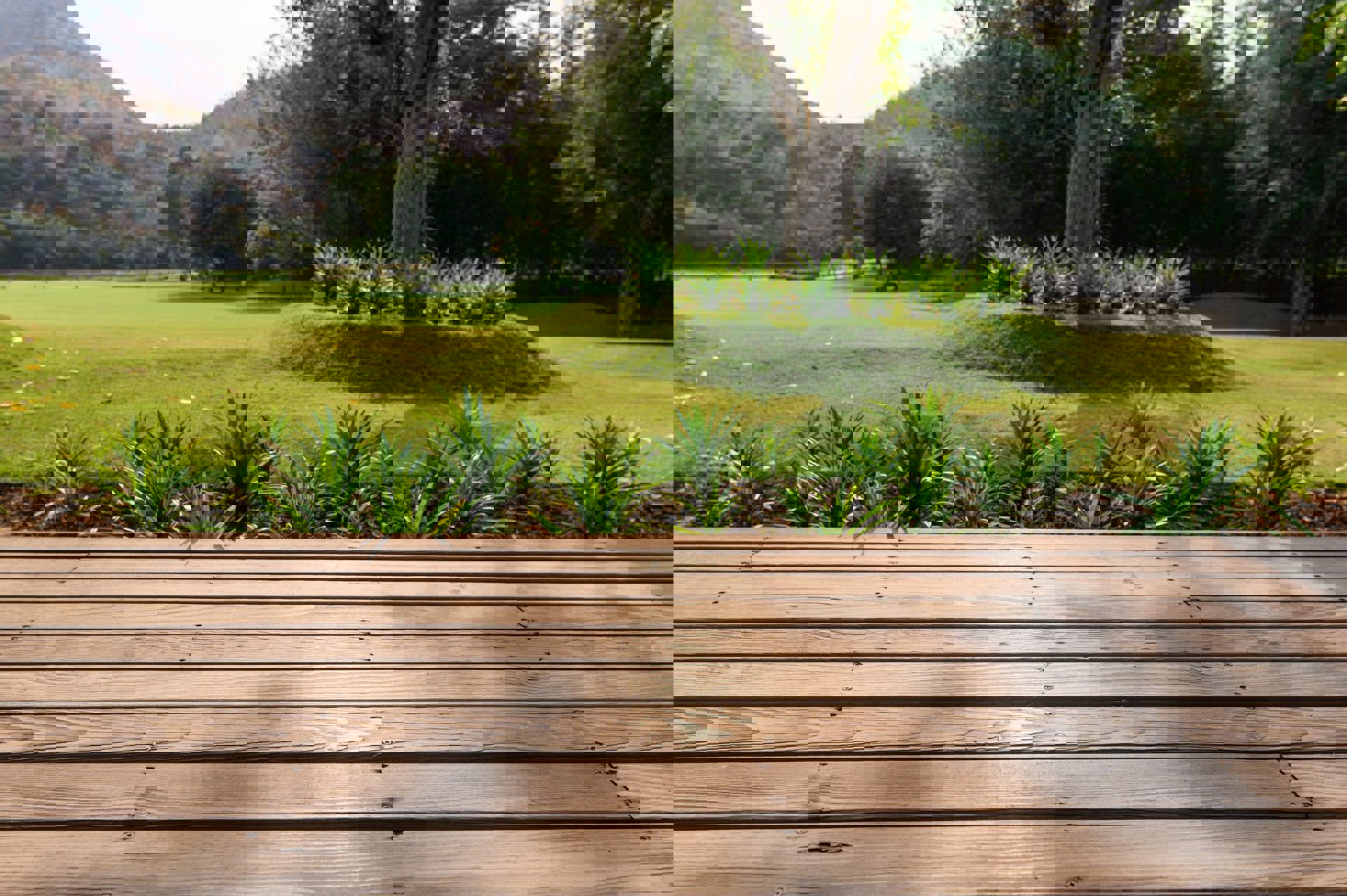 An outdoor deck is located next to a plant bed.