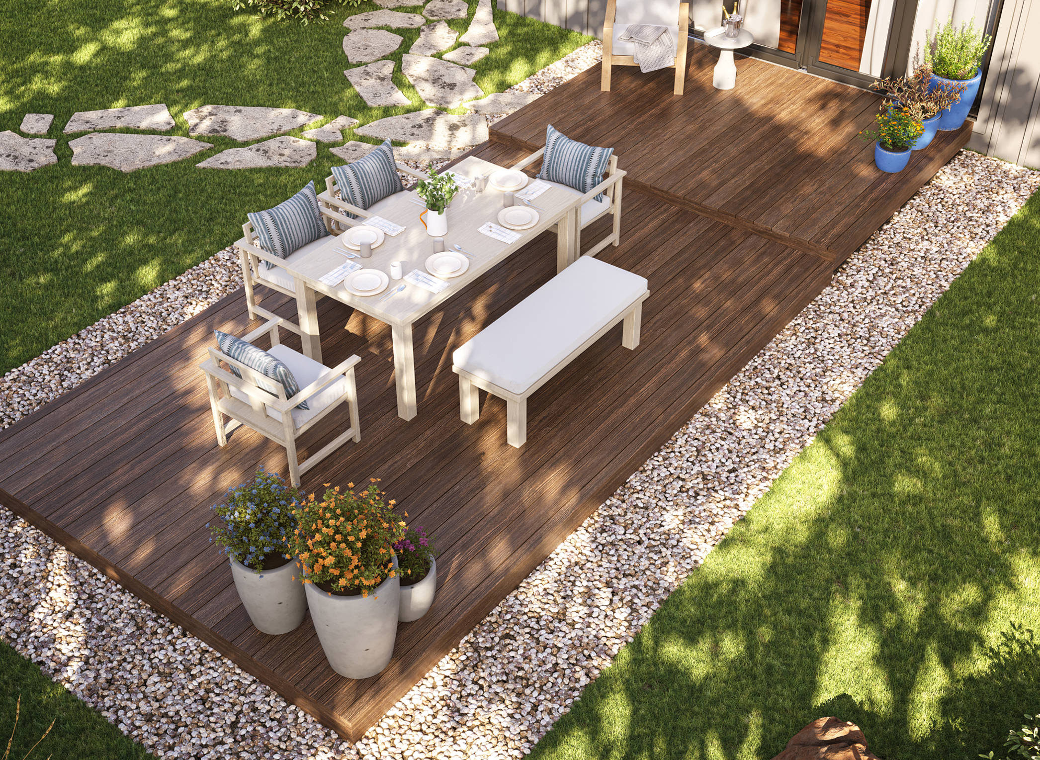 The image is taken from an aerial view, showing an outdoor seating area. There is a deck that is embedded in a gravel area, surrounded by grass.