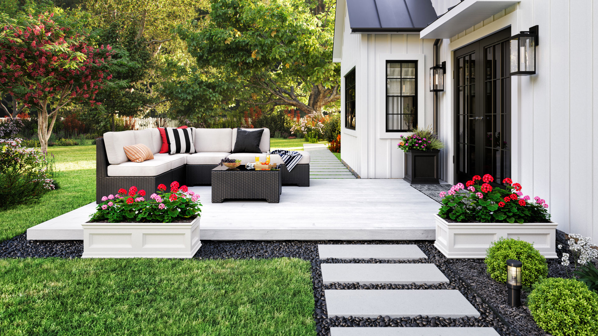 The image above shows an outdoor patio attached to a white house. The white deck holds a sofa and table. It sits atop gravel surrounded by grass.